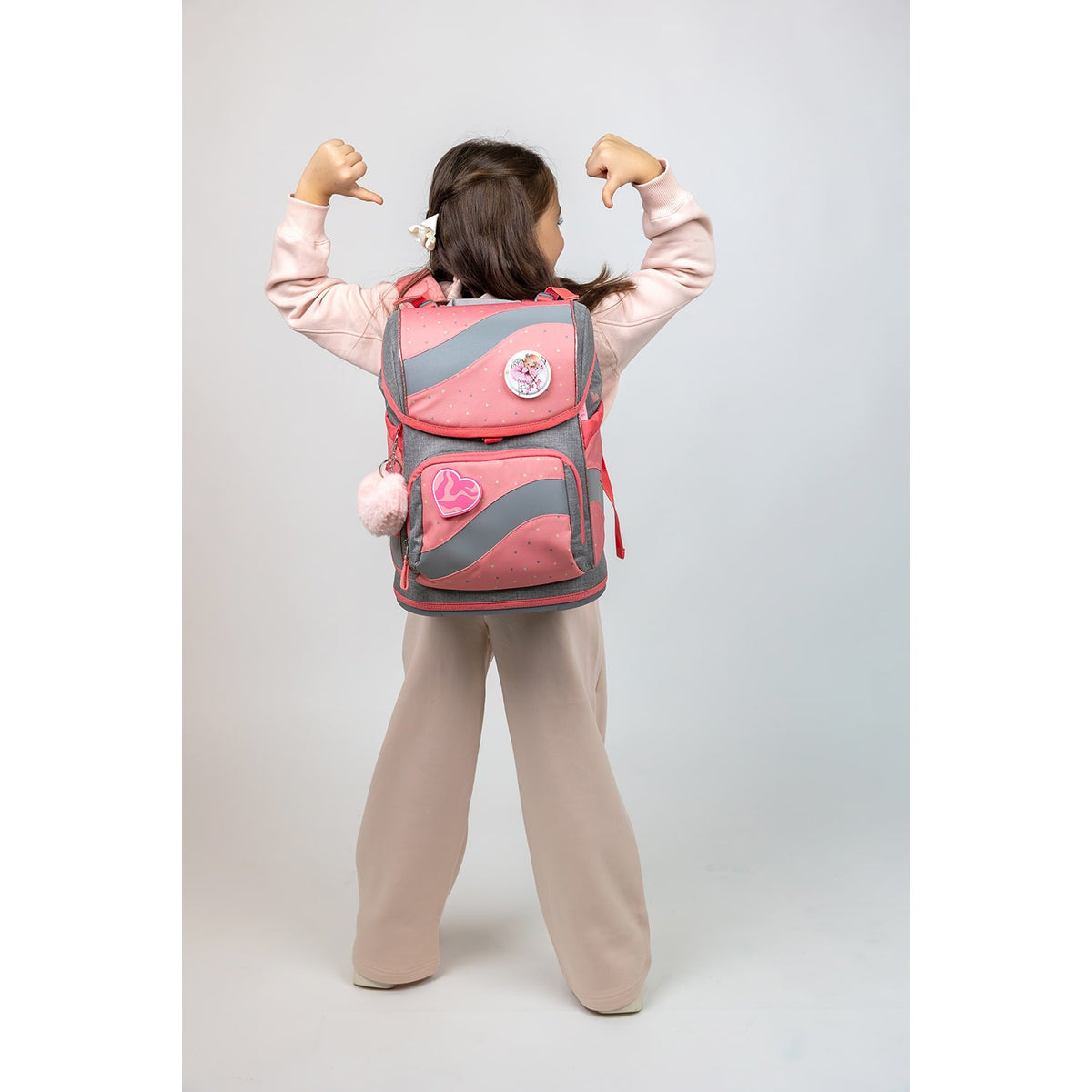 A young girl proudly displays the Belmil Smarty Minimal Triangels Ergonomic School Bag Set – 5-Piece Set with 9 Interchangeable Patches and Hip Belt, showcasing its ergonomic design and stylish appearance.