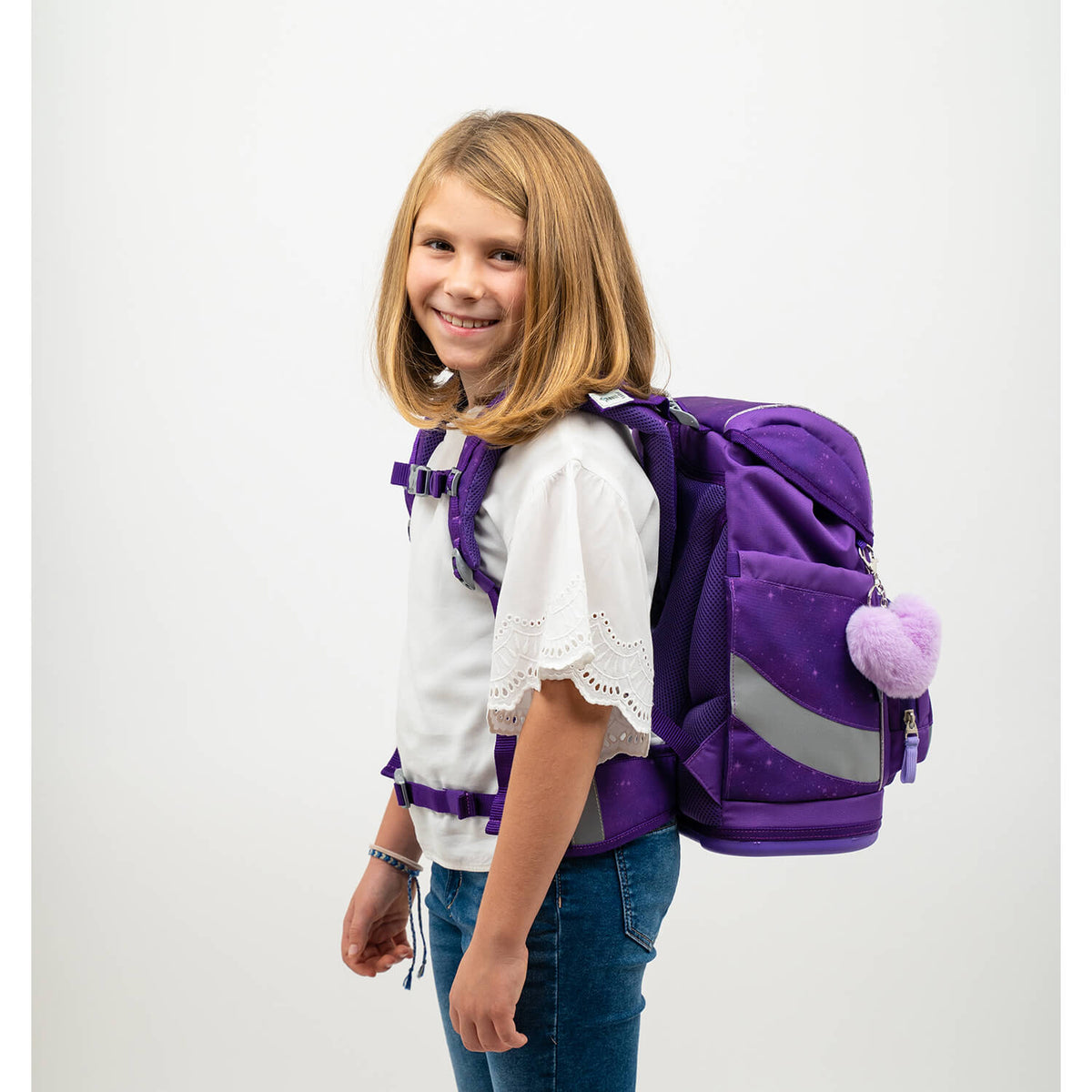 Girl showcasing the Belmil Smarty Purple Sky Ergonomic School Bag Set – 5-Piece Set with 9 Interchangeable Patches and Hip Belt, displayed comfortably on her back. This lightweight school bag is ideal for the 2025 school year, highlighted in purple with patch options, available for SALE.